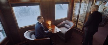 Movie still from “Murder on the Orient Express” (2017), directed by Kenneth Branagh – A man sitting at a table in front of a window; Wide shot, High angle
