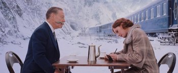 Movie still from “Murder on the Orient Express” (2017), directed by Kenneth Branagh – A man and a woman sitting at a table; Medium shot, Over the shoulder angle