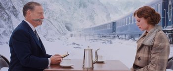 Movie still from “Murder on the Orient Express” (2017), directed by Kenneth Branagh – A person sitting at a table with a cup of coffee; Wide shot, High angle