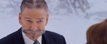 Movie still from “Murder on the Orient Express” (2017), directed by Kenneth Branagh – A person wearing a suit and tie; Close Up shot, Over the shoulder angle