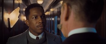Movie still from “Murder on the Orient Express” (2017), directed by Kenneth Branagh – A man wearing a suit and tie talking to another man; Close Up shot, Over the shoulder angle