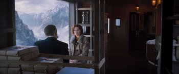 Movie still from “Murder on the Orient Express” (2017), directed by Kenneth Branagh – A woman standing in front of a window looking out at the mountains; Medium shot, Over the shoulder angle