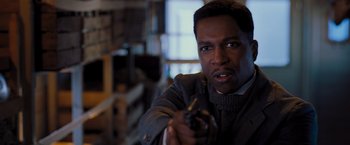 Movie still from “Murder on the Orient Express” (2017), directed by Kenneth Branagh – A man holding a gun in a room; Close Up shot, Over the shoulder angle