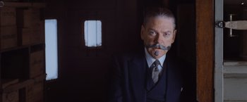 Movie still from “Murder on the Orient Express” (2017), directed by Kenneth Branagh – A man in a suit and tie with a fake mustache; Close Up shot, Low angle