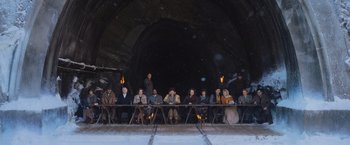 Movie still from “Murder on the Orient Express” (2017), directed by Kenneth Branagh – A group of people sitting at a table in front of a tunnel; Wide shot, High angle