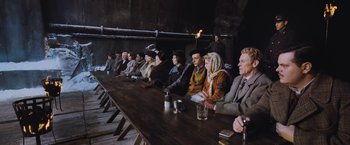 Movie still from “Murder on the Orient Express” (2017), directed by Kenneth Branagh – A group of people sitting around a long table; Wide shot, High angle