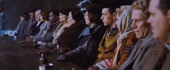 Movie still from “Murder on the Orient Express” (2017), directed by Kenneth Branagh – A group of people sitting in a row at a table; Medium shot, Low angle