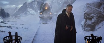 Movie still from “Murder on the Orient Express” (2017), directed by Kenneth Branagh – A man standing in front of a train on a train track; Medium shot, Low angle