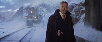 Movie still from “Murder on the Orient Express” (2017), directed by Kenneth Branagh – A man standing in front of a train; Medium shot, Low angle