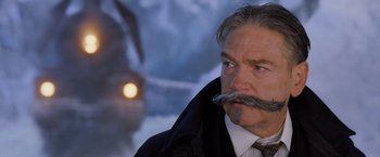 Movie still from “Murder on the Orient Express” (2017), directed by Kenneth Branagh – A person wearing a suit and tie; Close Up shot, Low angle