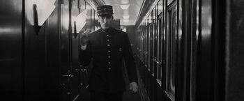 Movie still from “Murder on the Orient Express” (2017), directed by Kenneth Branagh – A man in a uniform walking down a hallway; Medium shot, Low angle