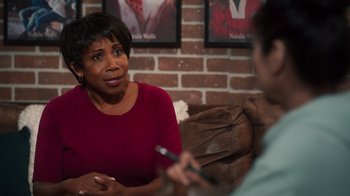 A woman sitting in front of a man holding a cell phone