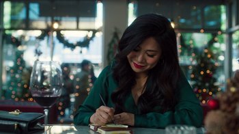 A woman sitting at a table writing on a notepad