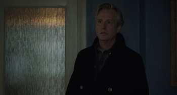 Movie still from “My Policeman” (2022), directed by Michael Grandage – A man standing in front of a window in a dark room; Close Up shot, Over the shoulder angle