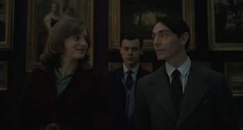 Movie still from “My Policeman” (2022), directed by Michael Grandage – A group of people standing next to each other in front of a painting; Close Up shot, Over the shoulder angle