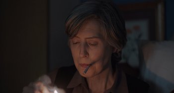 Movie still from “My Policeman” (2022), directed by Michael Grandage – An older woman is smoking a cigarette in the dark; Close Up shot, Over the shoulder angle