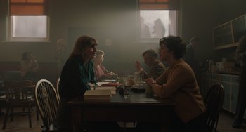 Movie still from “My Policeman” (2022), directed by Michael Grandage – A group of people sitting at a table talking to each other; Medium shot, Over the shoulder angle
