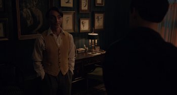 Movie still from “My Policeman” (2022), directed by Michael Grandage – A man standing in front of a table with a lamp on top of it; Medium shot, Over the shoulder angle