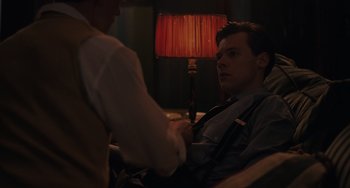 Movie still from “My Policeman” (2022), directed by Michael Grandage – Two men shaking hands in front of a red lamp; Medium shot, Over the shoulder angle