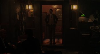 Movie still from “My Policeman” (2022), directed by Michael Grandage – A man in a suit and tie standing in front of a door; Wide shot, Low angle
