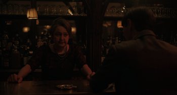 Movie still from “My Policeman” (2022), directed by Michael Grandage – A woman sitting at a table with a man in front of her; Medium shot, Over the shoulder angle