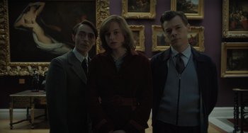 Movie still from “My Policeman” (2022), directed by Michael Grandage – A group of people standing next to each other in a room; Medium shot, Low angle