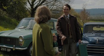 Movie still from “My Policeman” (2022), directed by Michael Grandage – A man and a woman standing in front of a green car; Medium shot, Over the shoulder angle