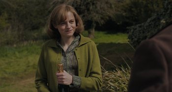 Movie still from “My Policeman” (2022), directed by Michael Grandage – A woman holding a piece of food in her hands; Medium shot, Over the shoulder angle