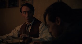 Movie still from “My Policeman” (2022), directed by Michael Grandage – A man sitting at a table with a glass of wine; Close Up shot, Over the shoulder angle