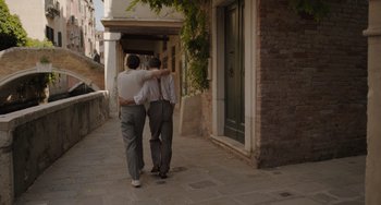Movie still from “My Policeman” (2022), directed by Michael Grandage – A couple of people that are walking down the street; Wide shot, Over the shoulder angle