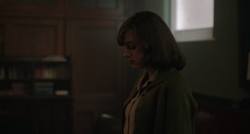 Movie still from “My Policeman” (2022), directed by Michael Grandage – A woman standing in a dark room with her head down; Medium shot, Over the shoulder angle