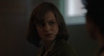 Movie still from “My Policeman” (2022), directed by Michael Grandage – A woman in a brown jacket is looking at the camera; Close Up shot, Over the shoulder angle