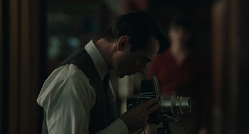 Movie still from “My Policeman” (2022), directed by Michael Grandage – A man in a vest and tie looking at a camera; Close Up shot, Over the shoulder angle