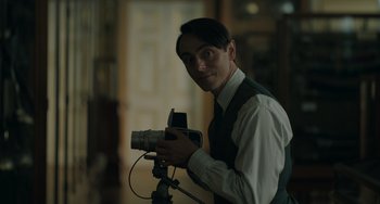 Movie still from “My Policeman” (2022), directed by Michael Grandage – A man holding a video camera in a room; Medium shot, Low angle