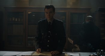 Movie still from “My Policeman” (2022), directed by Michael Grandage – A man in a uniform standing in front of a desk; Medium shot, Over the shoulder angle