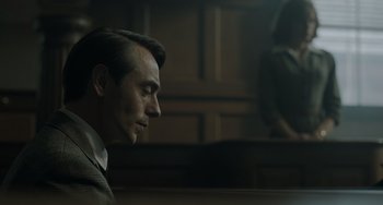 Movie still from “My Policeman” (2022), directed by Michael Grandage – A person wearing a suit in a room; Close Up shot, Low angle