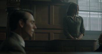 Movie still from “My Policeman” (2022), directed by Michael Grandage – A man and a woman standing in front of a judge; Medium shot, Over the shoulder angle