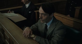 Movie still from “My Policeman” (2022), directed by Michael Grandage – A man sitting at a table with a watch in front of him; Close Up shot, Low angle
