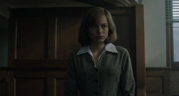 Movie still from “My Policeman” (2022), directed by Michael Grandage – A woman in a gray jacket standing in a room; Medium shot, Low angle