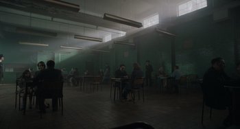 Movie still from “My Policeman” (2022), directed by Michael Grandage – A group of people sitting at tables in a room; Extreme Wide shot, High angle