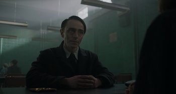 Movie still from “My Policeman” (2022), directed by Michael Grandage – A man sitting at a table in front of a window; Medium shot, Over the shoulder angle