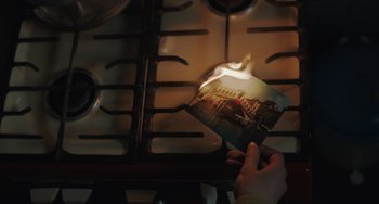 Movie still from “My Policeman” (2022), directed by Michael Grandage – A person holding a picture of a building on fire; Extreme Close Up shot, High angle