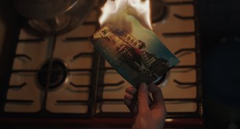 Movie still from “My Policeman” (2022), directed by Michael Grandage – A person holding an old photo in front of a fire; Extreme Close Up shot, High angle