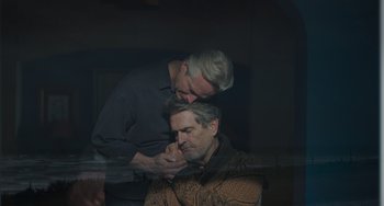 Movie still from “My Policeman” (2022), directed by Michael Grandage – A man is touching another man's face in the dark; Medium shot, High angle