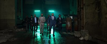 Movie still from “My Spy” (2020), directed by Peter Segal – A group of men in suits and ties walking across a wet floor; Wide shot, Low angle