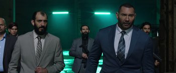 Movie still from “My Spy” (2020), directed by Peter Segal – A group of men in suits and ties standing in front of a green light; Medium shot, Low angle