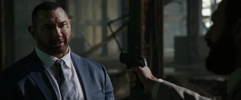 Movie still from “My Spy” (2020), directed by Peter Segal – A man wearing a suit and tie holding a video game controller; Close Up shot, Over the shoulder angle