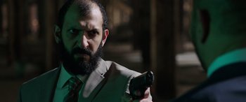 Movie still from “My Spy” (2020), directed by Peter Segal – A bearded man holding a gun in a dark room; Close Up shot, Over the shoulder angle