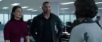 Movie still from “My Spy” (2020), directed by Peter Segal – A man in a leather jacket standing in an office; Medium shot, Over the shoulder angle