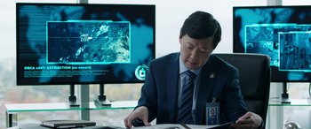 Movie still from “My Spy” (2020), directed by Peter Segal – A man sitting at a desk in front of a computer monitor; Medium shot, Over the shoulder angle